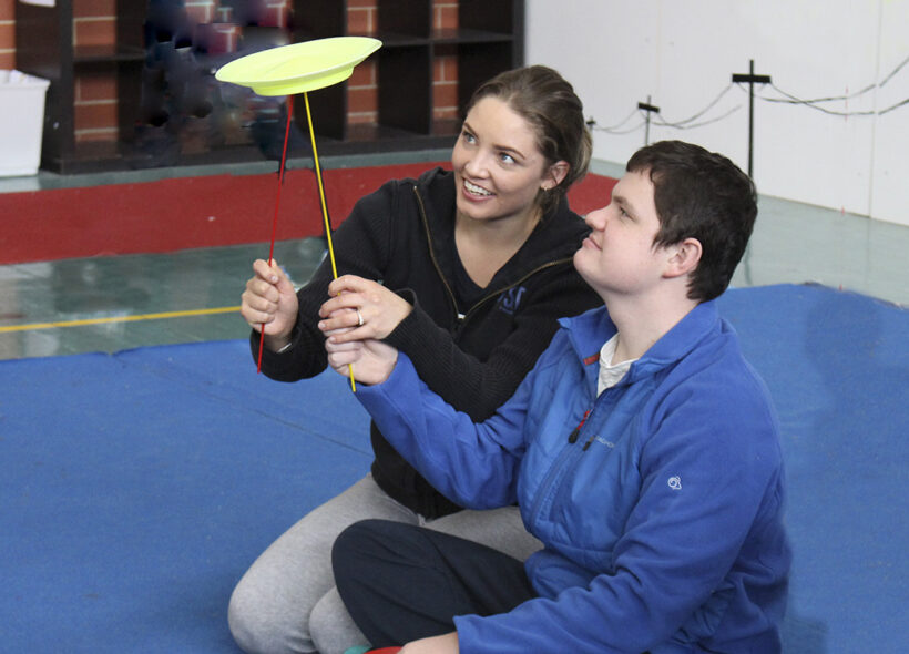 Trainer and young woman plate spinning