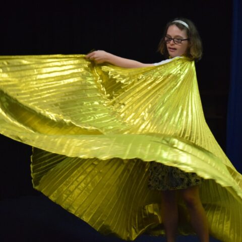 A young woman swirling a log golden cape