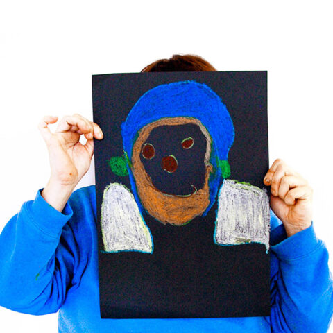 An Art + Connect workshop participant with their self-portrait.