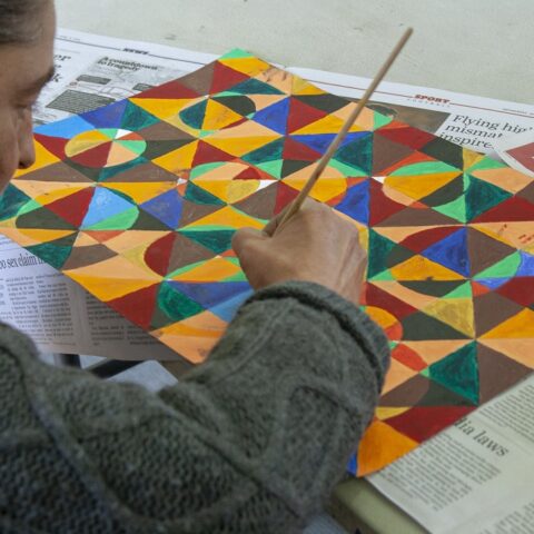 A woman painting a geometric based artwork.