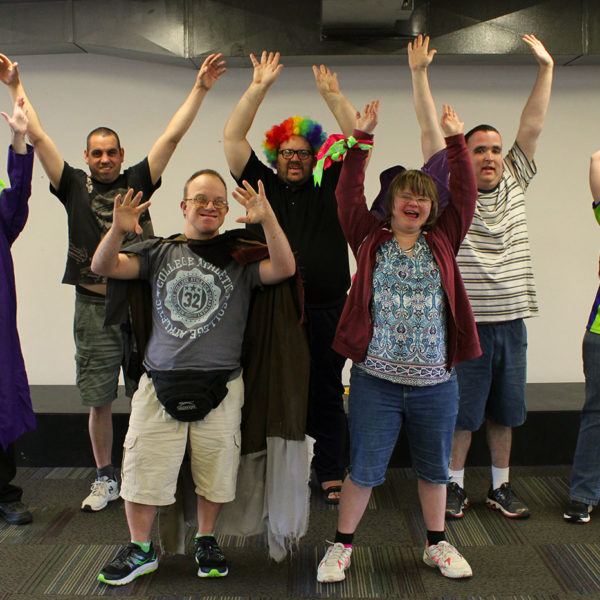 A group of people smile and wave at the camera