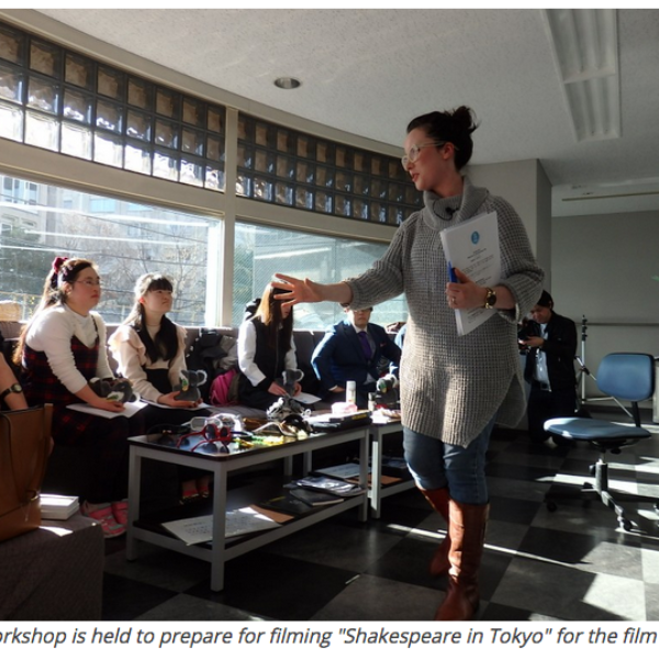 Woman holding script under arm talking to a group of young people.