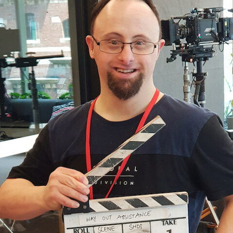 Young man holding clapper board