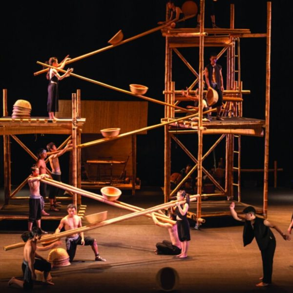 Circus performers on a stage making an impressive high structure out of bamboo poles, baskets and scaffolding