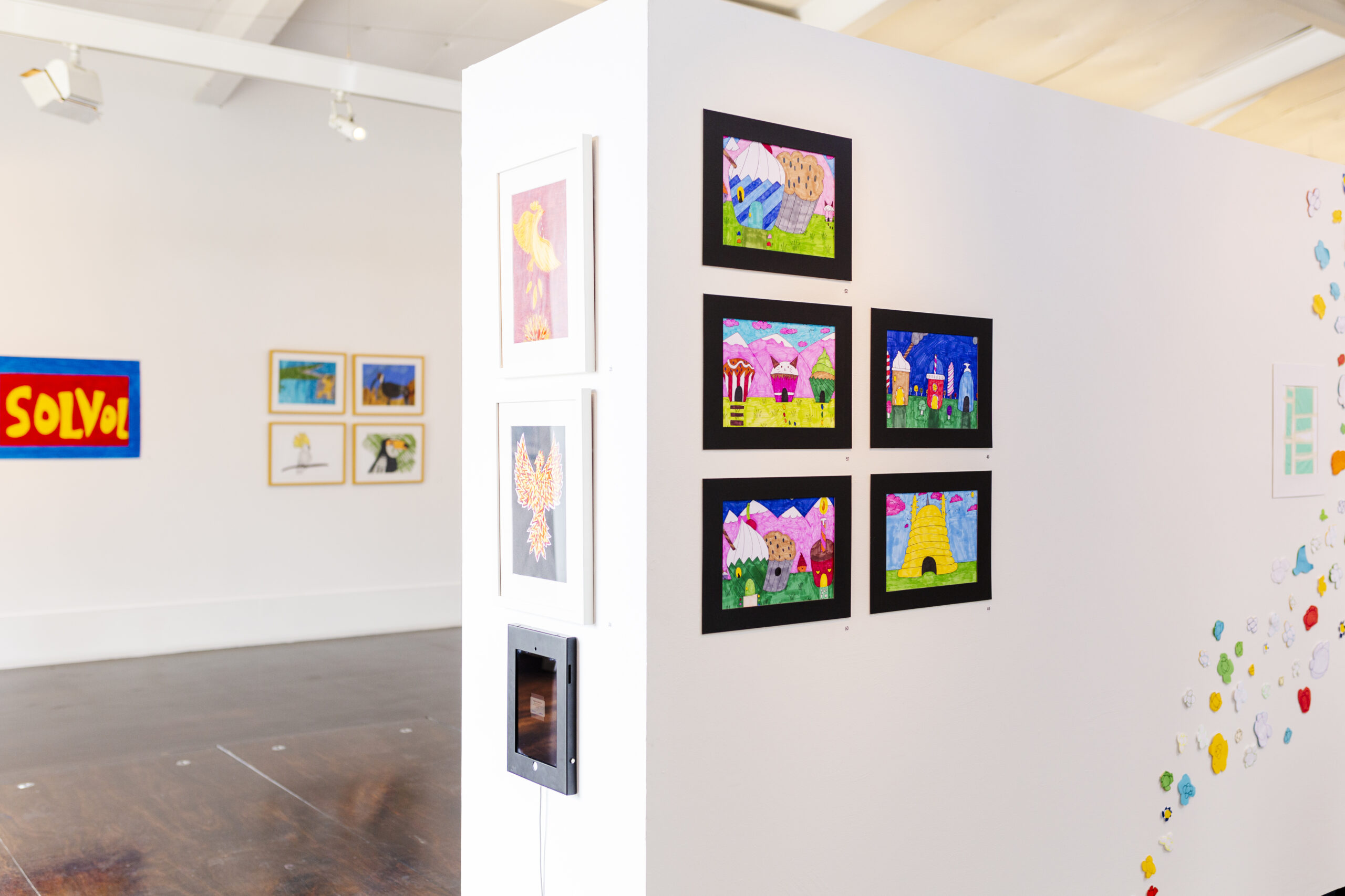 A series of Art works displayed in gallery on white walls. 