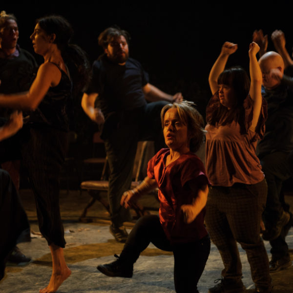 A dark image of a group of people moving and swinging their arms