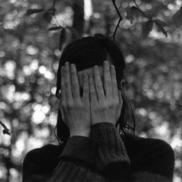 Choreographer Mette Edvardsen stands in the woods covering her face with her hands