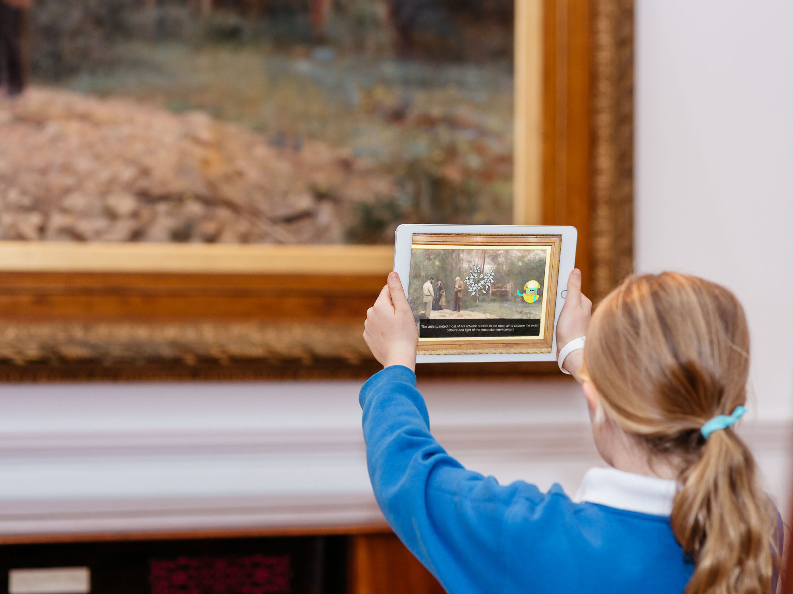 A young person holds an iPad with the Orby program, learning about Frederick McCubbin's 'A bush burial'