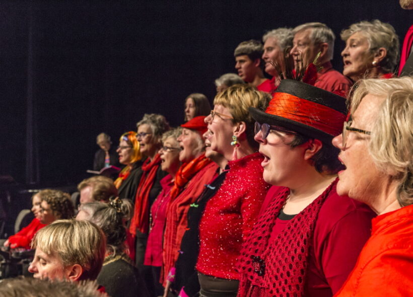 Side on view as a choir dressed in red and black sing