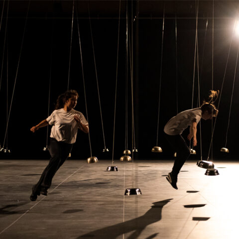 Dancers running dynamically under stage lights between small hanging domes