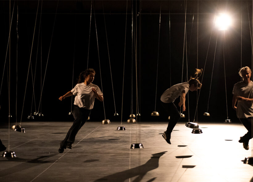 Dancers running dynamically under stage lights between small hanging domes