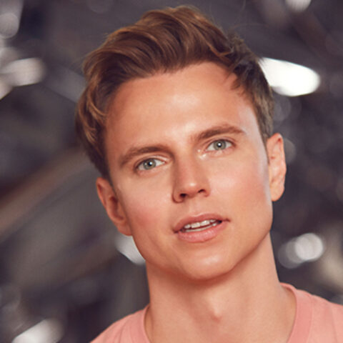 Pictured is Shane Jenek (also known as Courtney Act) as their masculine presenting self.