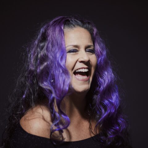 Woman with long curly bright purple hair laughing