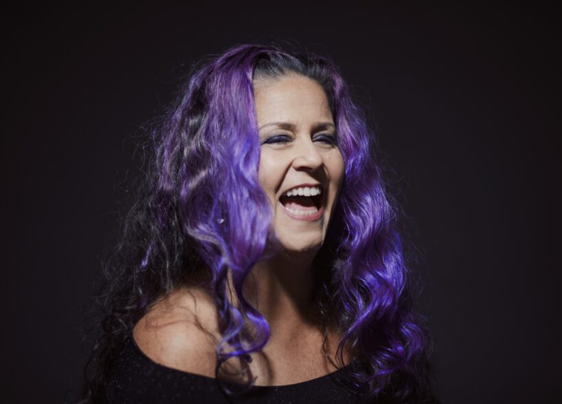 Woman with long curly bright purple hair laughing