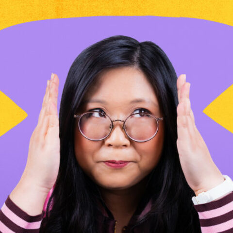 Jennifer Wong holding her hands up on either side of her glasses, a backdrop with yellow arrows around her head.