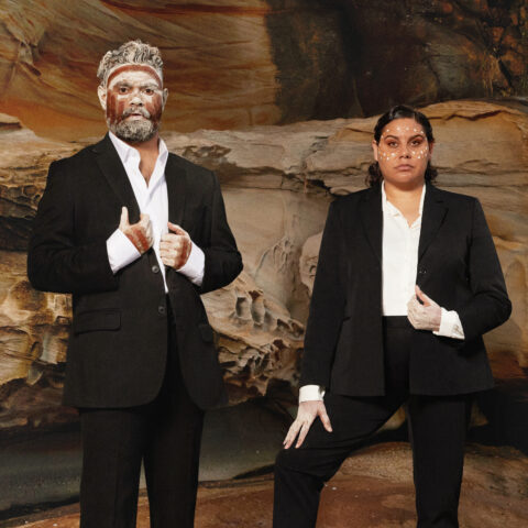 Beau Dean Riley Smith and Dalara Williams stand on rocks wearing suits and body and face paint