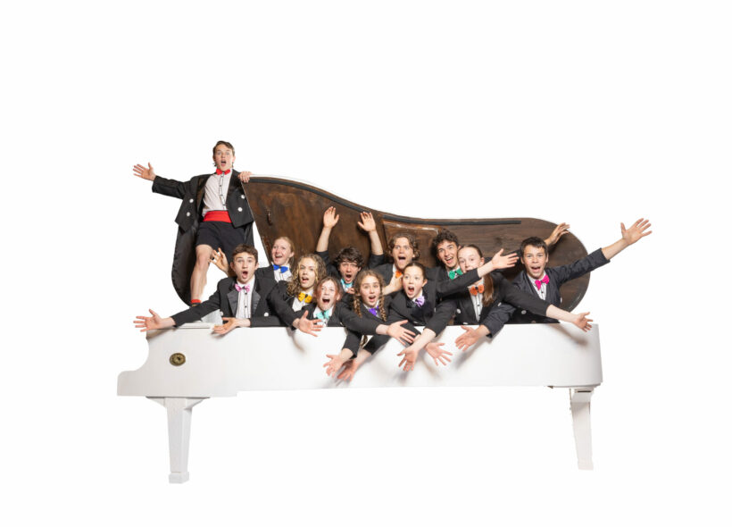 Flying Fruit Fly Circus' performers pose in suits inside a white piano