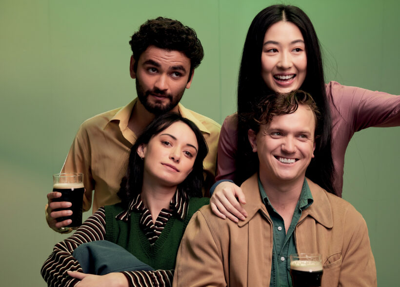Four friends smiling with two holding beer