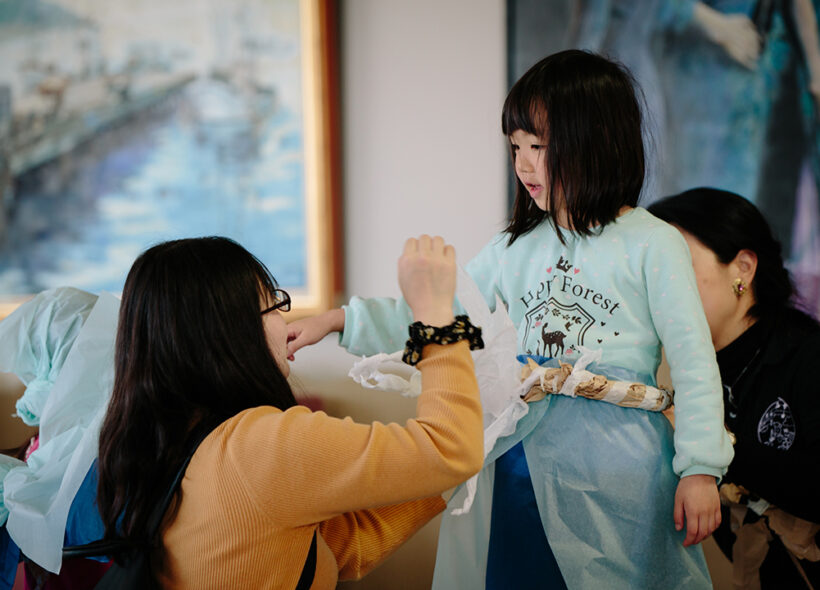 A Paper Planet Production Image. A parent gestures to their child. They are illuminated by soft light. Photo: Ai Ueda