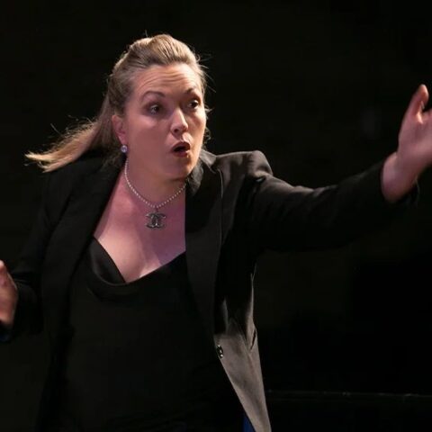 Sarah-Grace Williams in a black suit conducts The Metropolitan Orchestra