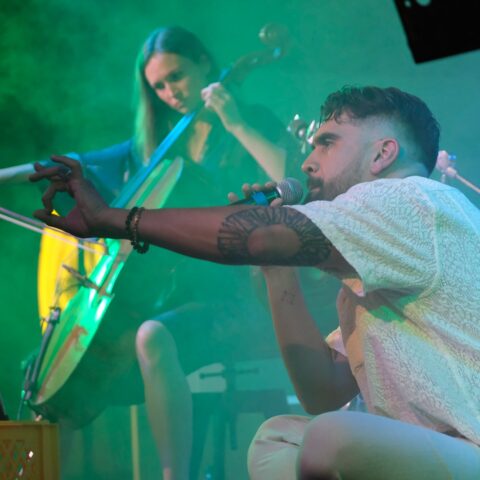 man crouching in front of woman playing a cello