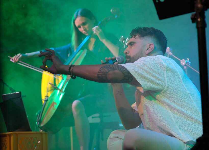 man crouching in front of woman playing a cello