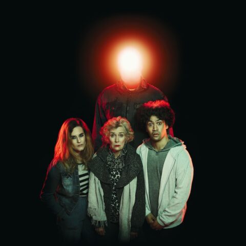 three people looking sad in front of a figure with a glowing red head