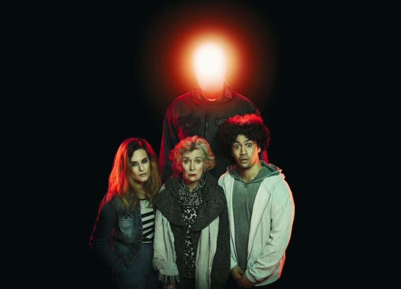 three people looking sad in front of a figure with a glowing red head