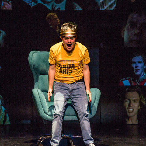 Male actor wearing crown playing Hamlet screams at audience 