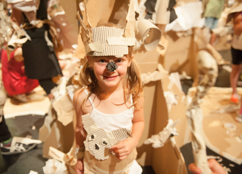 A Paper Planet production photo: A child wears a paper costume and mask against the backdrop of the set. Photo: Sarah Walker
