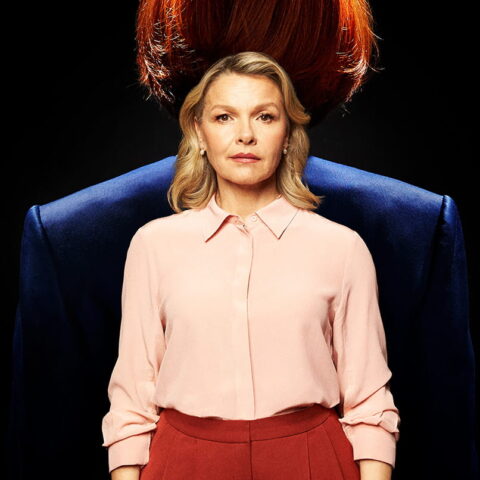Justine Clarke stands facing forward. Behind her is the bust of Julia Gillard facing away from her