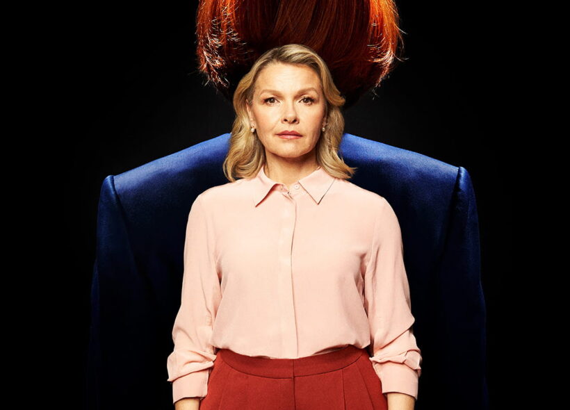 Justine Clarke stands facing forward. Behind her is the bust of Julia Gillard facing away from her