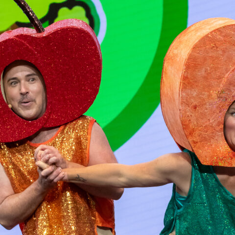 One actor in a apple costume, another in a peach costume, mid action 