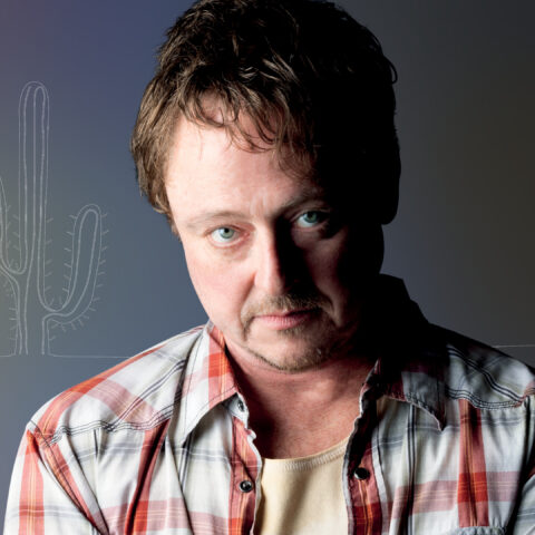man wearing checkered shirt looking menacingly at the camera