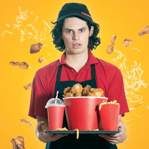 Young man in fast food uniform holding a tray of deep fried fast food