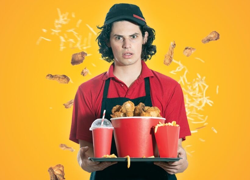 Young man in fast food uniform holding a tray of deep fried fast food