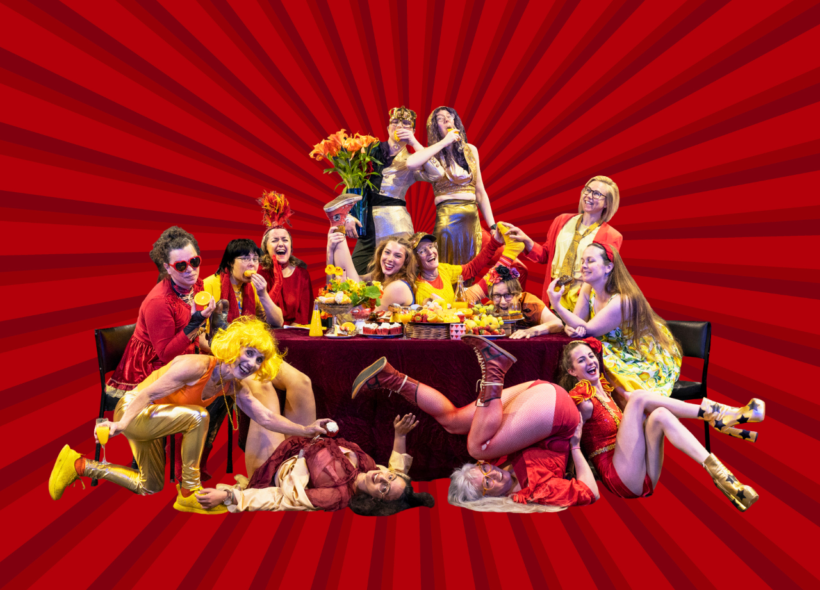 A group of women having a lavish banquet wearing red and yellow circus costumes.