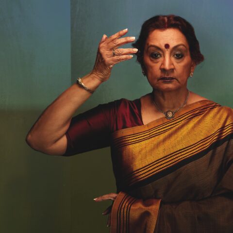 Elegant woman in a traditional saree, adorned with jewelry, holds a graceful pose.