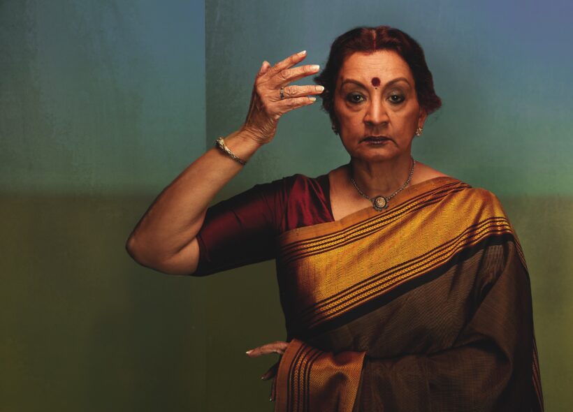 Elegant woman in a traditional saree, adorned with jewelry, holds a graceful pose.