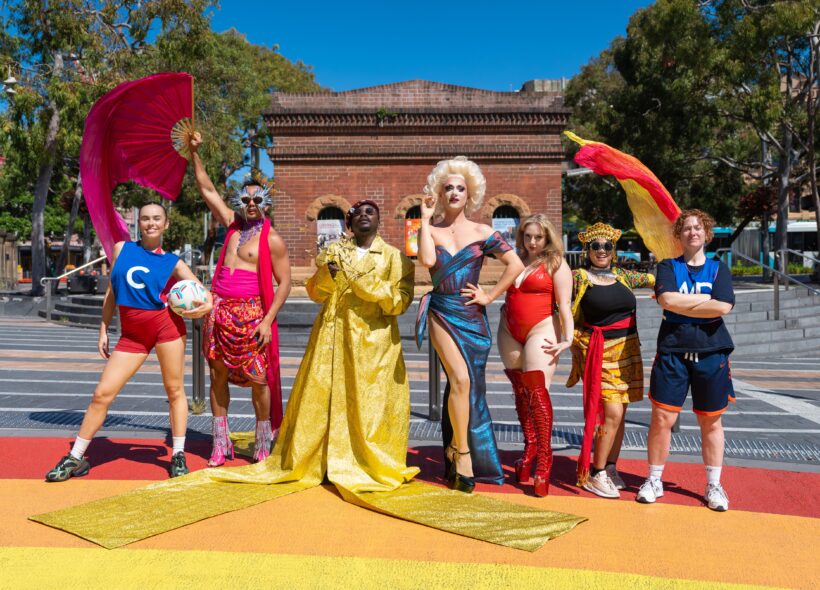 Promo image of artists posed on the rainbow walkway outside Qtopia Sydney
