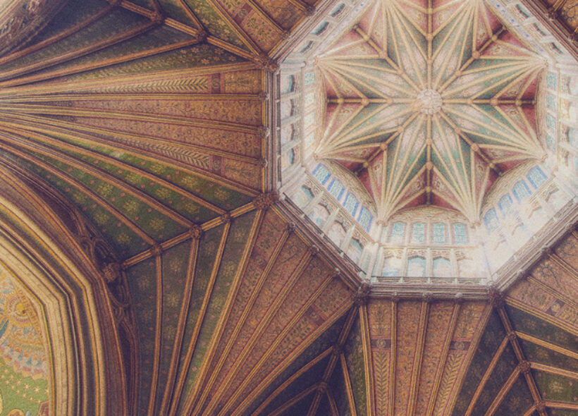 Ornate cathedral ceiling with intricate geometric patterns, stained glass windows, and warm tones of green and brown, conveying a sense of awe.