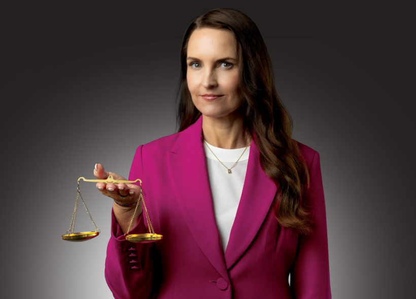 A professional woman in a pink suit holds the scales of justice 