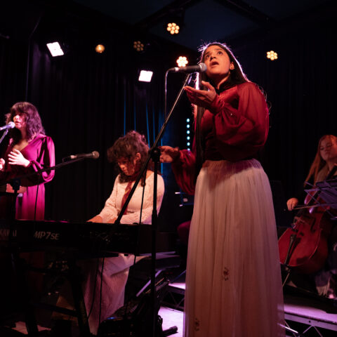 A lively performance by women, harmonizing together on stage, radiating joy and energy