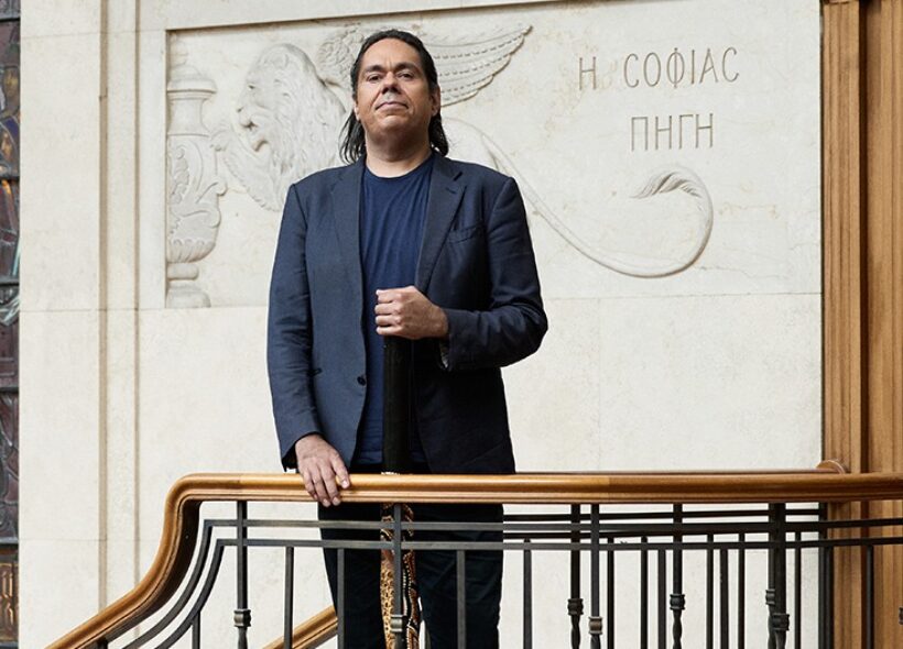 A man stands confidently on a staircase holding a yidaki 