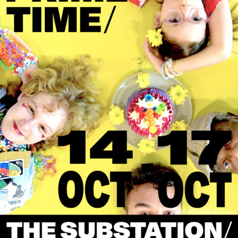 Four people across a range of ages are laying around a cake while looking up at the camera