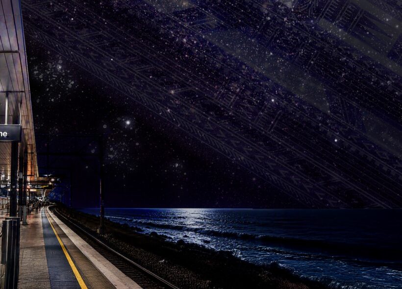 An empty Western Line platform stretches beside a dark ocean under a brilliant, star-filled sky, creating a quiet, dreamlike nighttime scene.